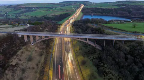 An aerial view of a concrete bridge running across a motorway.