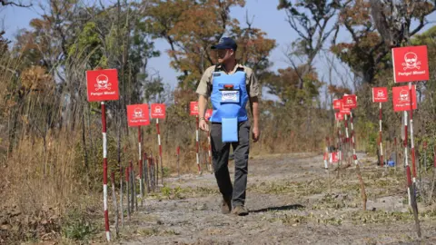 PA Media Prince Harry following a path cleared in a minefield in Angola