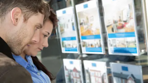 Young couple look at houses for sale in an estate agent's window