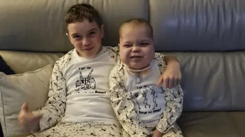 Family photo Two children sit on a sofa in pyjamas smiling