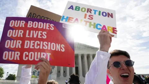 Getty Images Abortion rights supporters hold placards on the day the Supreme Court justices hear oral arguments over the legality of Idaho's Republican-backed, near-total abortion ban in medical-emergency situations, at the U.S. Supreme Court in Washington, DC