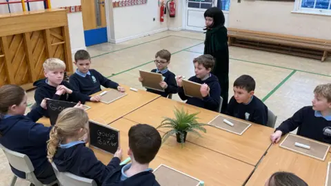 Pupils gathered around a table with chalkboards