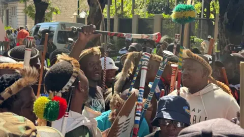 BBC / Thuthuka Zondi protesters in cultural headdresses and holding instruments