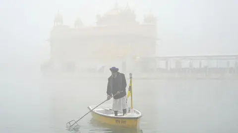 AFP via Getty Images A Sikh volunteer cleans the holy lake on the occasion of Maghi festival or Makar Sankranti, amid dense fog at the Golden Temple in Amritsar on January 14, 2026. 