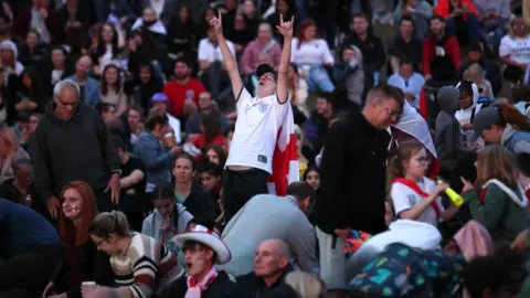 PA Media A person cheers during the game