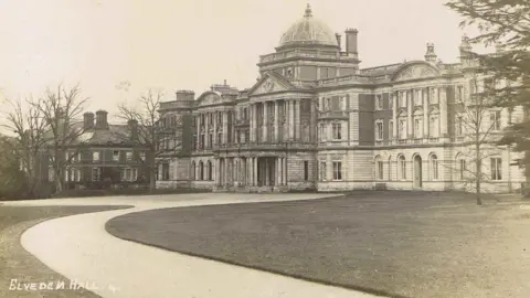 Peter Bance Collection Maharajah Duleep Singh exhibition. Old image of Elveden Hall. It is a stately home with a path and grass outside it.