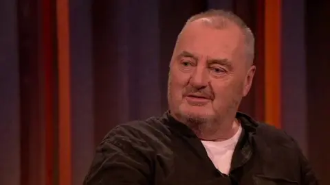 Tommy Tiernan Show RTÉ The actor, Jon Kenny seen here on The Tommy Tiernan Show on RTÉ One in June 2019, in a white tee shirt and brown shirt