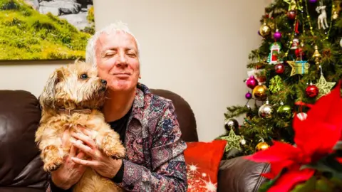 Brian Hurton with his dog, pictured in front of a Christmas tree. 