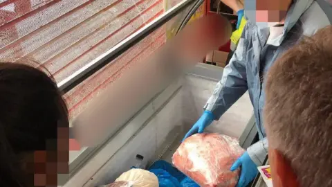 Northamptonshire Police Officers lifting meat out of a freezer