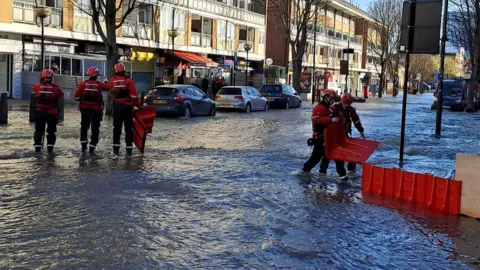 Crews standing in flood water.