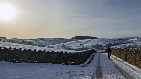 PA Media A cyclist on the snow at Blackmoss Reservoir in Barley, Pendle, Lancashire