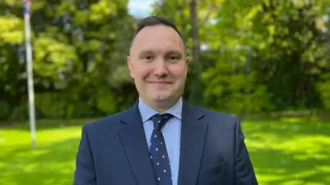 BBC/Kate Bradbrook Mark Thomas with short dark hair wearing a blue jacket