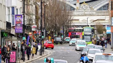 A view of Brighton train station, with cars and buses running up and down Queen's Road.