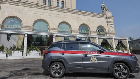A grey car law enforcement car is parked outside a building in Moscow
