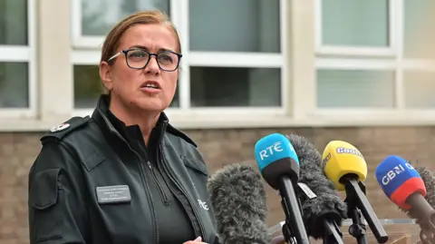 Pacemaker ACC Jones wearing a green police jacket stood in front of microphones