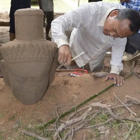 AFP An archaeologist cleans the head of a statue after its excavation from the ground at the complex in Siem Reap province (01 August 2017)