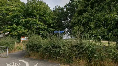 The entrance to a nature reserve with trees blocking the view to the main area

