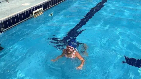 A young girl swimming in a pool.