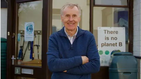 Martin Giles/BBC Dave Green beside a "There is no Planet B" poster