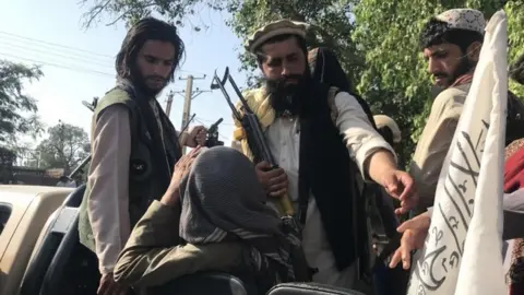 EPA Taliban fighters displaying their flag on outskirts of Kabul on 15 August 2021