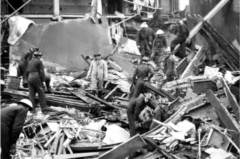 Getty Images October 1940: Rescue workers sift through the rubble of Hoxton hospital in London, bombed the previous night in a German air raid. (Photo by Reg Speller/Fox Photos/Getty Images)