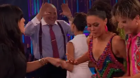 BBC Studios Wynne Evans appears to hold his hands up for a high-five towards Katya Jones