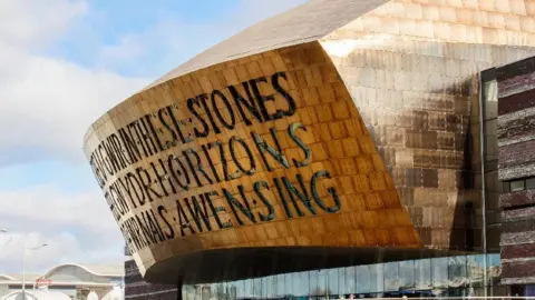 Getty Images Exterior view of the Welsh Millennium Centre, an arts centre in the Cardiff Bay area, which has a large gold-coloured roof with writing on it