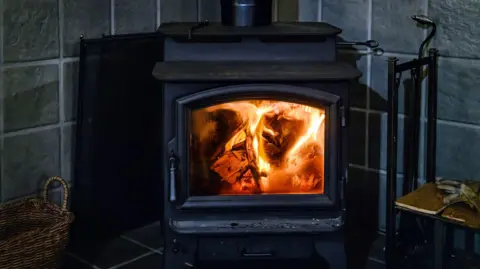 A domestic wood burner alight with the door open.