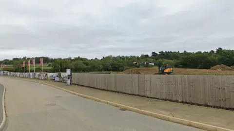 Diggers on the estate, with fencing along the road side