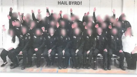 West Virginia Department of Military Affairs Employees at the West Virginia Division of Corrections and Rehabilitation giving the salute below a sign that reads "HAIL BYRD!"