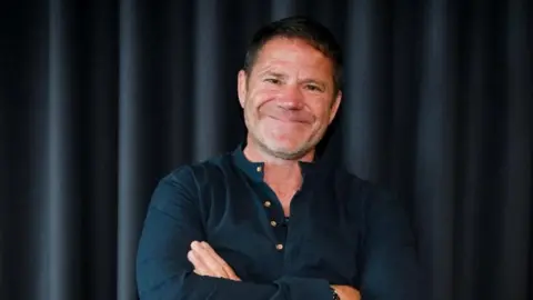 Sarah Jeynes/BBC A man, Steve Backshall, stood with his arms crossed.