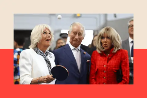AFP via Getty Images Queen Camilla plays table tennis, next to King Charles III and Brigitte Macron, during a visit to the Saint-Denis, a northern suburb of Paris, on 21 September 2023.