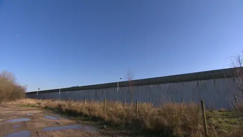 The prison wall at Garth surrounded by fencing and scrubs