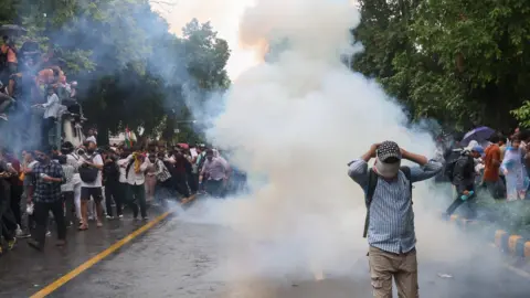 EPA/Shutterstock Indian security personnel use tear gas and lathi charge as they attempt to stop Cockroach Janta Party's(CJP) supporters during a march toward the Parliament in New Delhi, India, 20 July 2026.