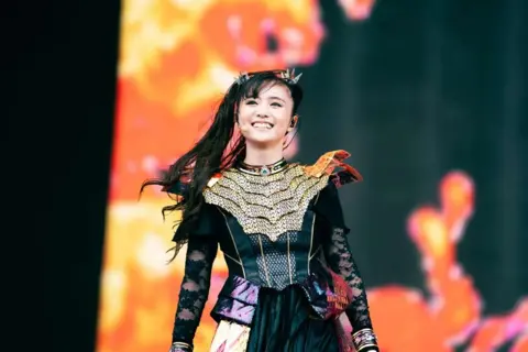 Roger Alarcon/Download Festival A woman in black costume smiling on stage. 