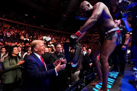 Getty Images Jon Jones celebrates by handing Trump his title