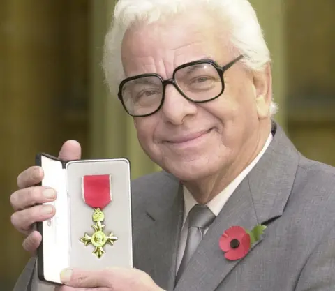 PA Media Barry Cryer showing his OBE awarded to him by Queen Elizabeth II at Buckingham Palace in 2001