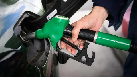 A person fills up their car with a petrol pump. 
