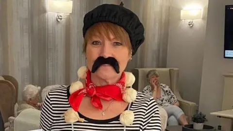 Lime Trees Care Home A woman in a striped top, black beret and fake moustache
