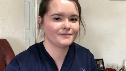 Nurse, Paige Calved looking directly into the camera. She is wearing her work uniform