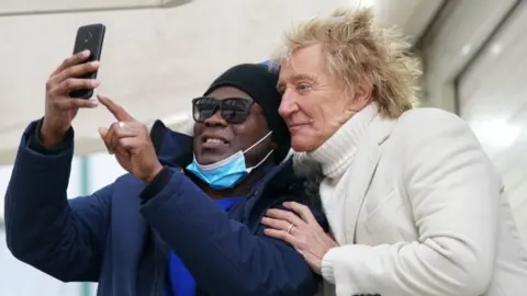 PA Media Sir Rod Stewart with scan patient Omarie Ryan