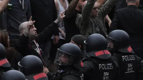 EPA Right wing protesters gesture towards police in riot gear as they gather at the place where a man was stabbed