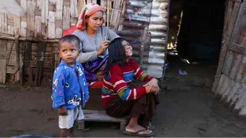 Getty Images Rohingya family gather outside their residence in Baw Du Pha IDP camp on December 18, 2021, in Sittwe, Rakhine State.