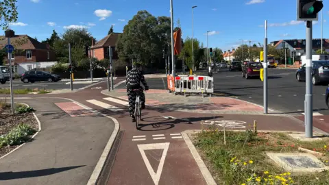 Jozef Hall/BBC A cyclist waiting for the green light to cross the junction