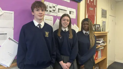 Three young people smiling in an office setting