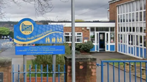 Blue railings at the entrance to a large brick school building with an entranceway set in to it