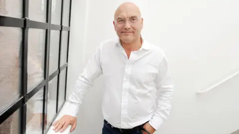 Gregg Wallace pictured at Radio 2 in 2019, standing on a staircase