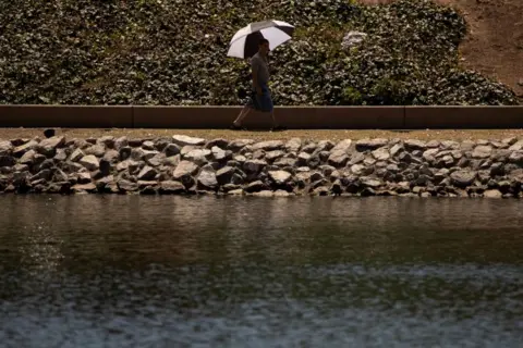 Reuters Man walks along path with black and white umbrella