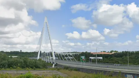 Google The Northern Spire is a modern bridge with two white pillars meeting above its centre and forming a triangle shape. 