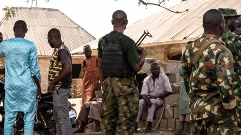 AFP via Getty Images Members of the army interact with residents following the attack in Woro, Kwara State 5 February 2026